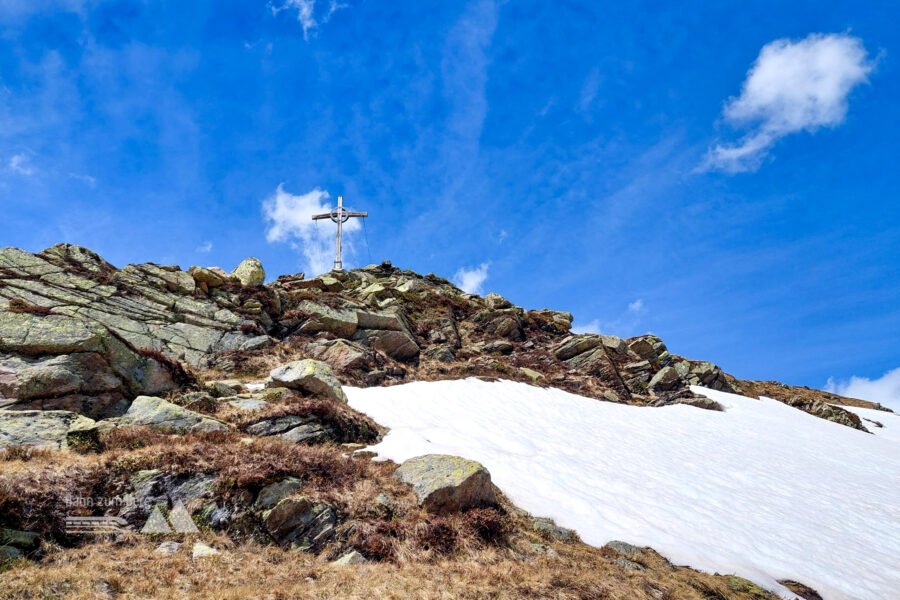 Blick zurück auf das Gipfelkreuz und die kleinen Felsen, die bei diesem Abstiegsweg zu überwinden sind. Foto: Alice Frischherz